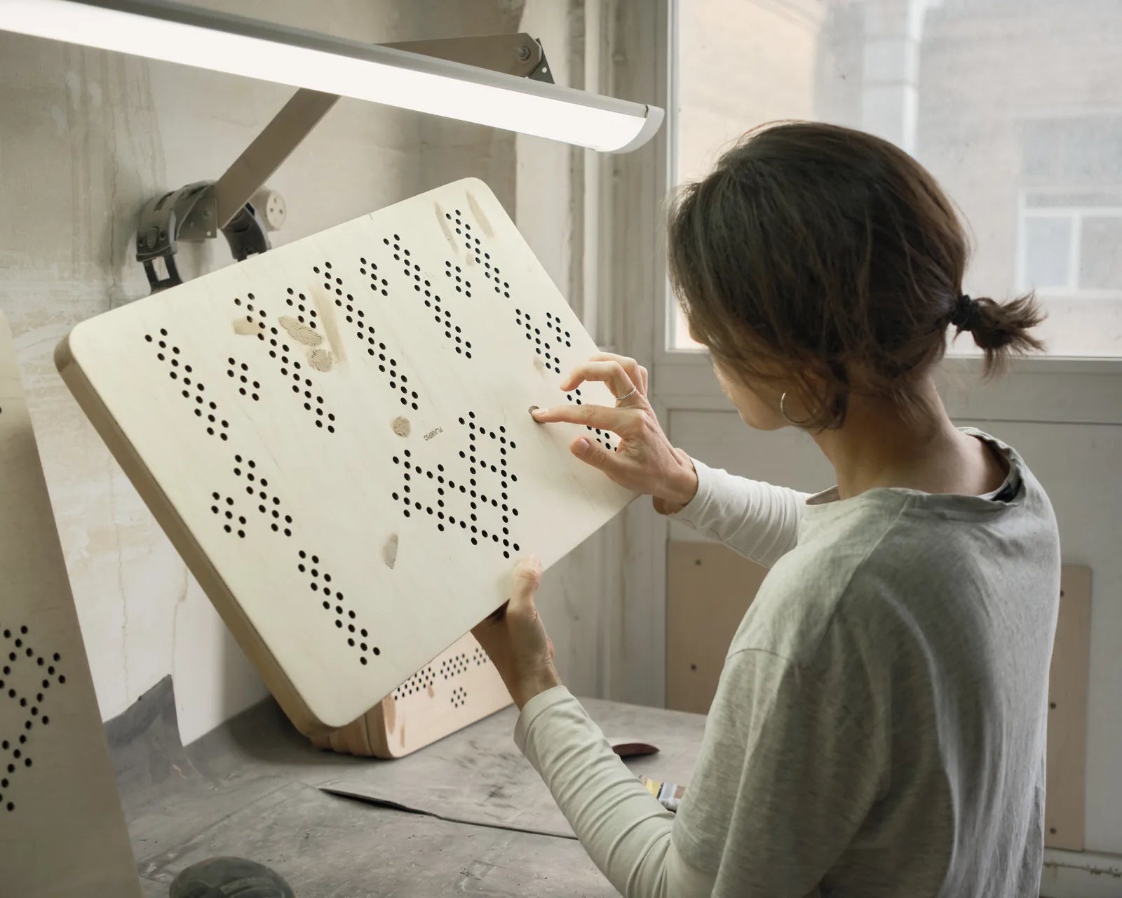 Inspecting a perforated top at the workbench.